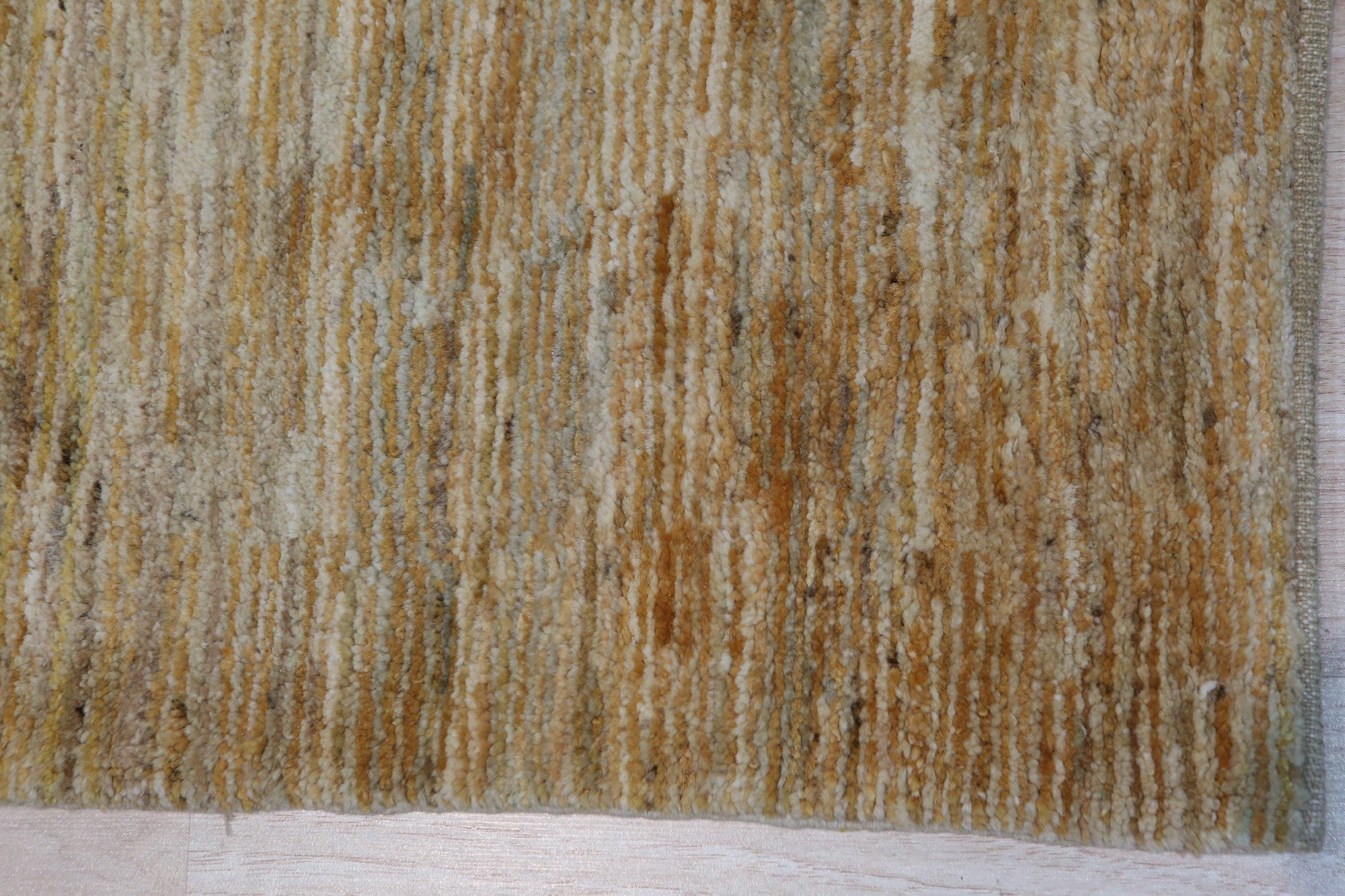 Trara Bianca Gold Hand Knotted Afghan Wool Rug displays intricate geometric patterns in cream and gold tones, hand-knotted from Afghan wool, grounding a bright living space with subtle elegance.