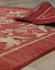 Majestic Artisan Red Hand Knotted Afghan Wool Rug, vibrant red and intricately patterned, lays elegantly within a well-lit interior, showcasing its luxurious texture and handcrafted detail.