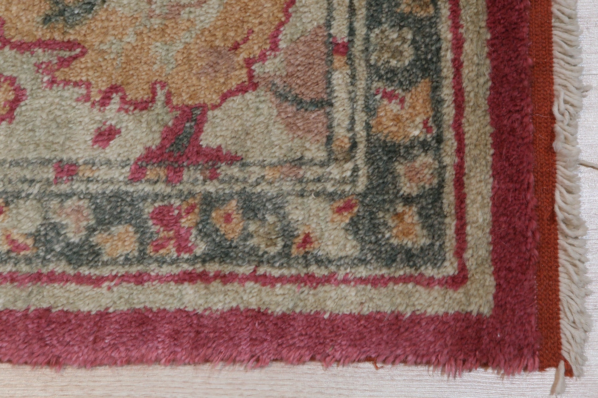 Opulent Oushak Red Hand Knotted Rug, displaying rich, warm red hues and intricate floral patterns, lies flat showcasing its hand-knotted construction and luxurious texture within a bright, naturally lit space.