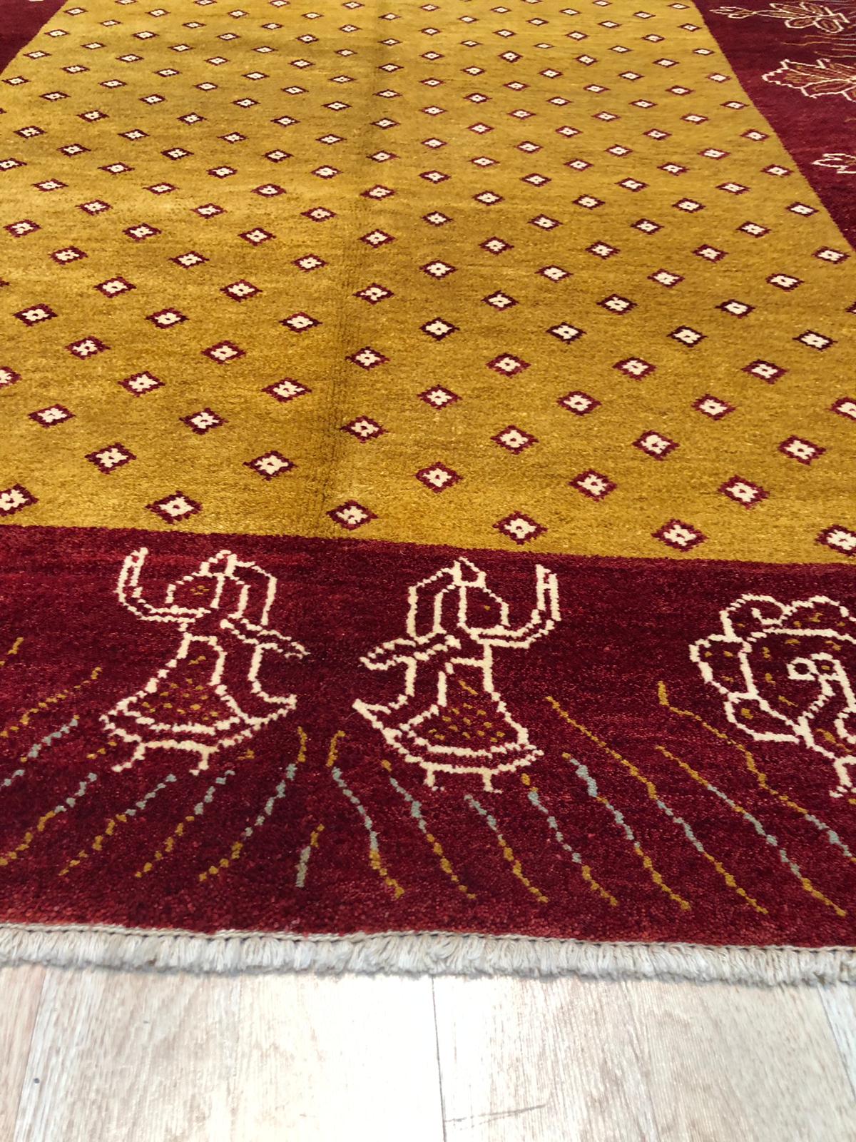 Artisan Quinn Yellow Hand Knotted Wool Rug, bathed in warm sunlight, anchors a bright living space. Its hand-knotted wool construction provides a plush texture underfoot, while subtle variations in yellow hues create a sophisticated, inviting atmosphere within the room.