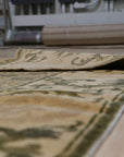 Classic Elena Green Hand Knotted Wool Rug, showcasing a lush green backdrop overlaid with an intricate, traditional floral pattern in muted tones, creating a timeless elegance under a soft, natural light.