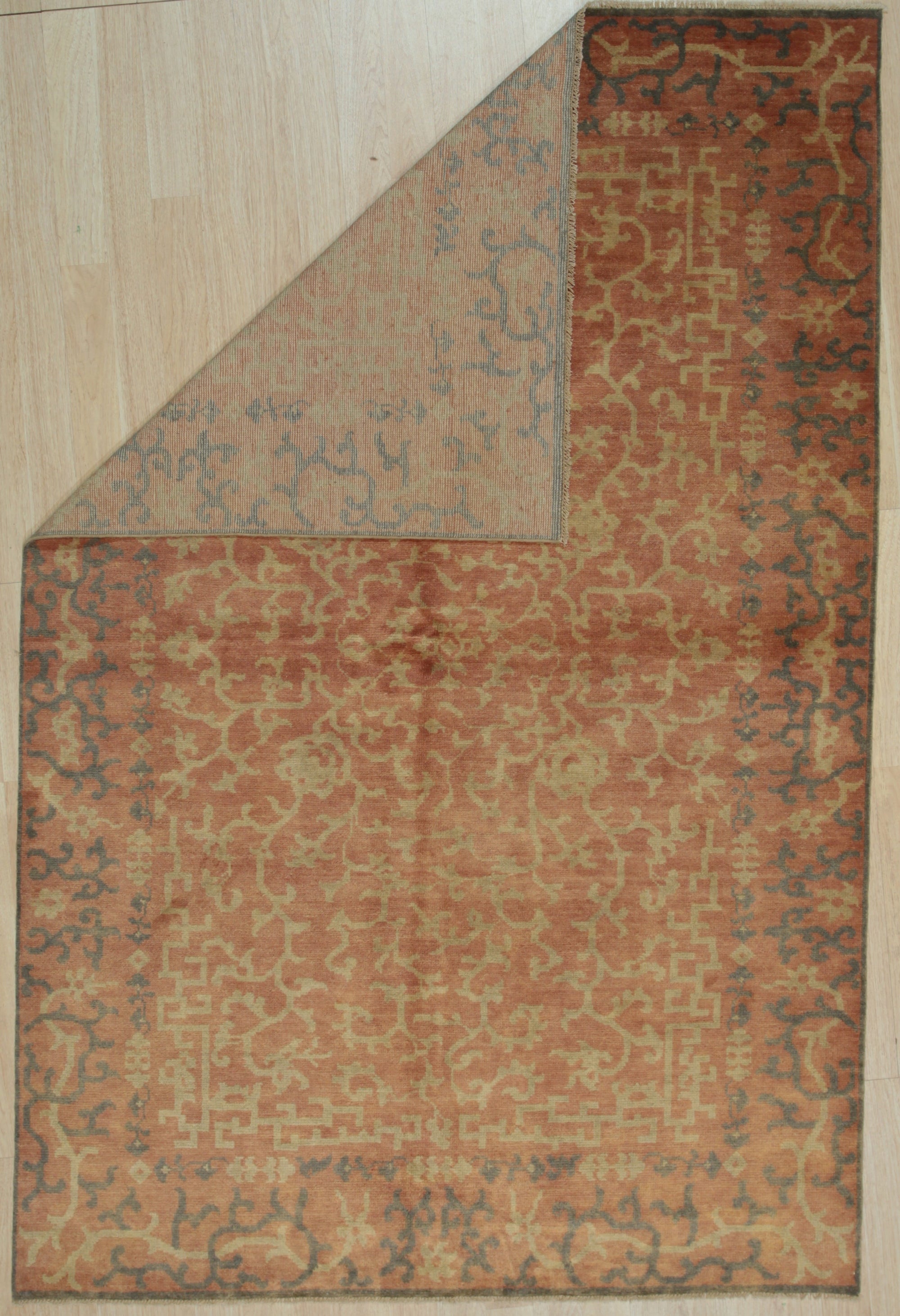 Lydia Jasmine Red Hand Knotted Wool Rug, showcasing intricate floral patterns in rich reds and earthy tones, adds warmth and elegance to a neutral room setting.
