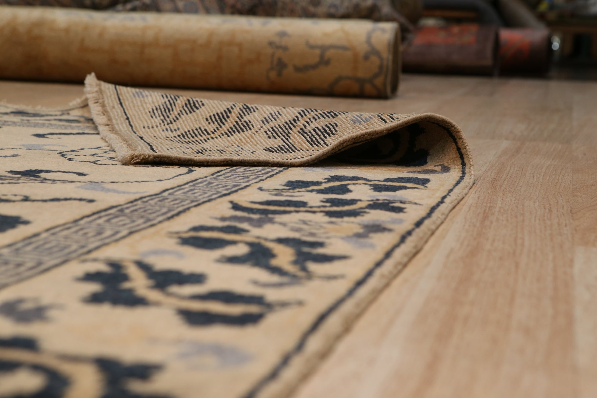 Willow Lydia Gold Hand Knotted Wool Rug, featuring a complex pattern of warm gold and neutral tones, anchoring a bright living room with contemporary furniture.