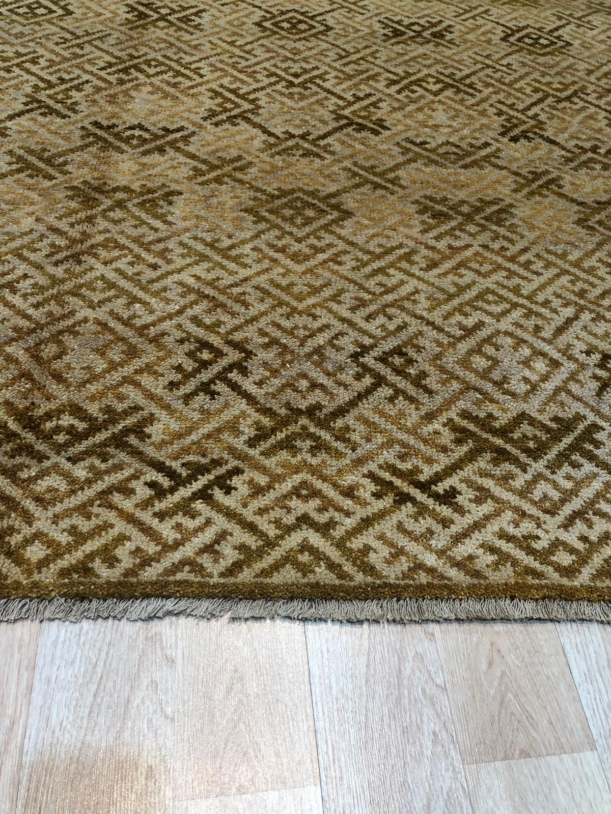 Rhea Majestic Brown Hand Knotted Wool Rug, its warm brown tones and hand-knotted texture grounding a living room scene with a neutral sofa and hardwood floors, showcasing its scale and integration into a modern interior.