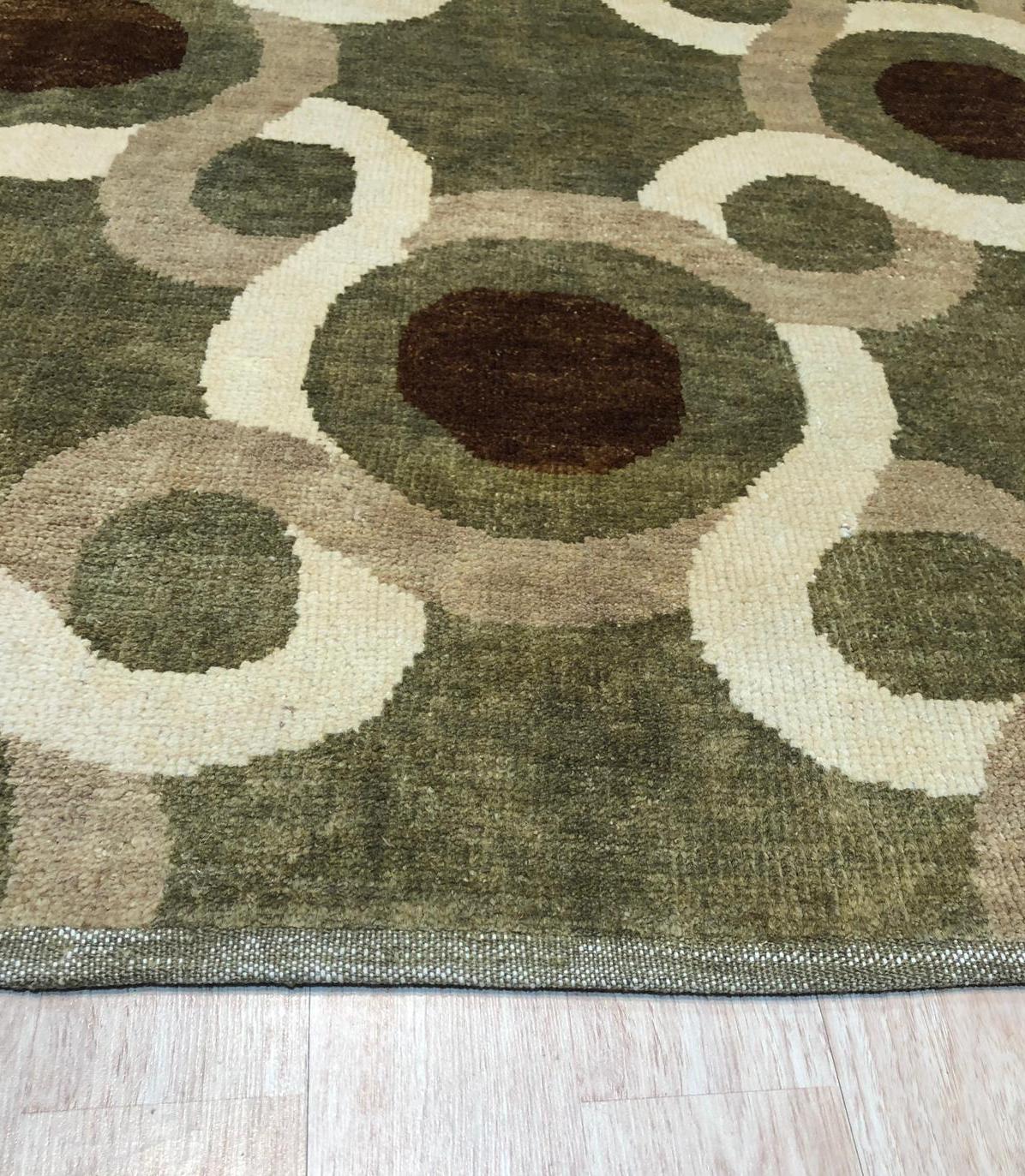 Talia Artistic Green Hand Knotted Wool Rug graces a living room, its verdant hues and artistic patterns grounding the space beneath a sleek, modern sofa. Soft wool texture and hand-knotted construction add depth to the room's sophisticated design.