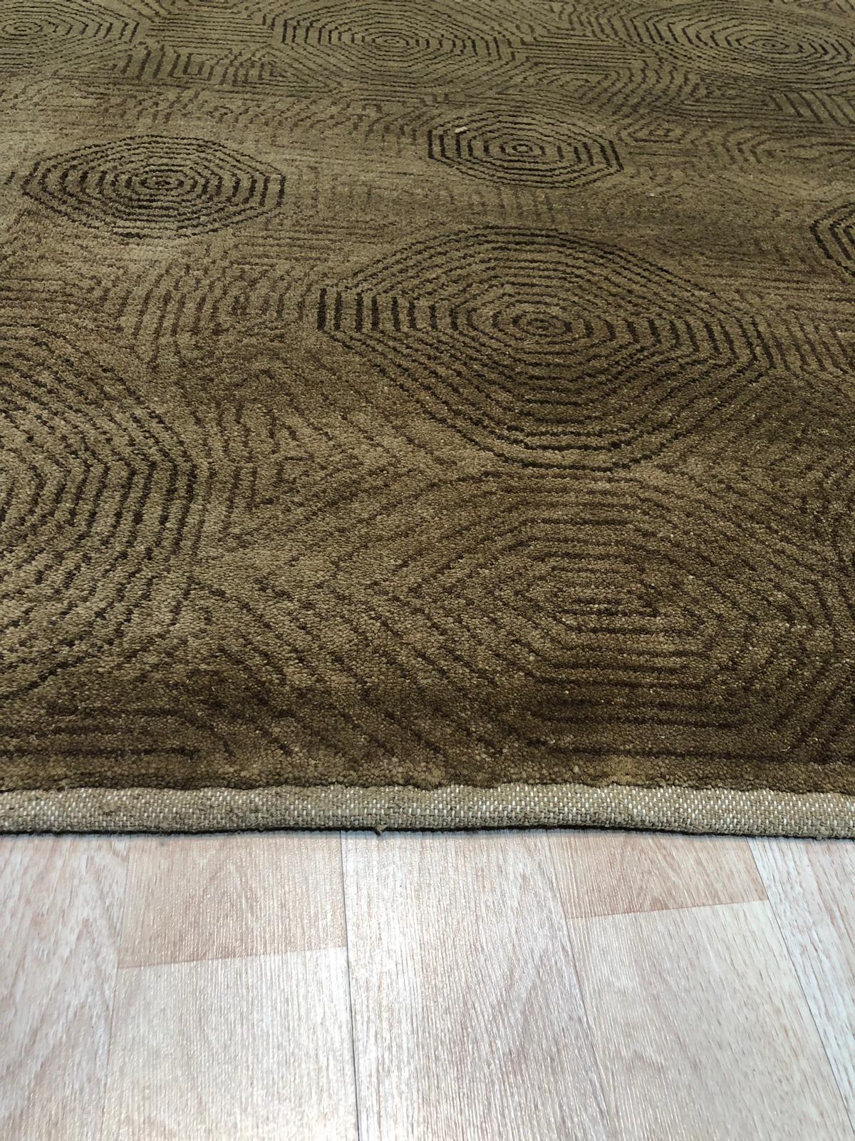 Exquisite Yara Brown Hand Knotted Wool Rug displayed in a warmly lit interior setting. The rug's earthy brown tones and intricate, hand-knotted wool construction complement the surrounding furniture and create an inviting atmosphere.