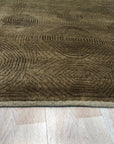 Exquisite Yara Brown Hand Knotted Wool Rug displayed in a warmly lit interior setting. The rug's earthy brown tones and intricate, hand-knotted wool construction complement the surrounding furniture and create an inviting atmosphere.