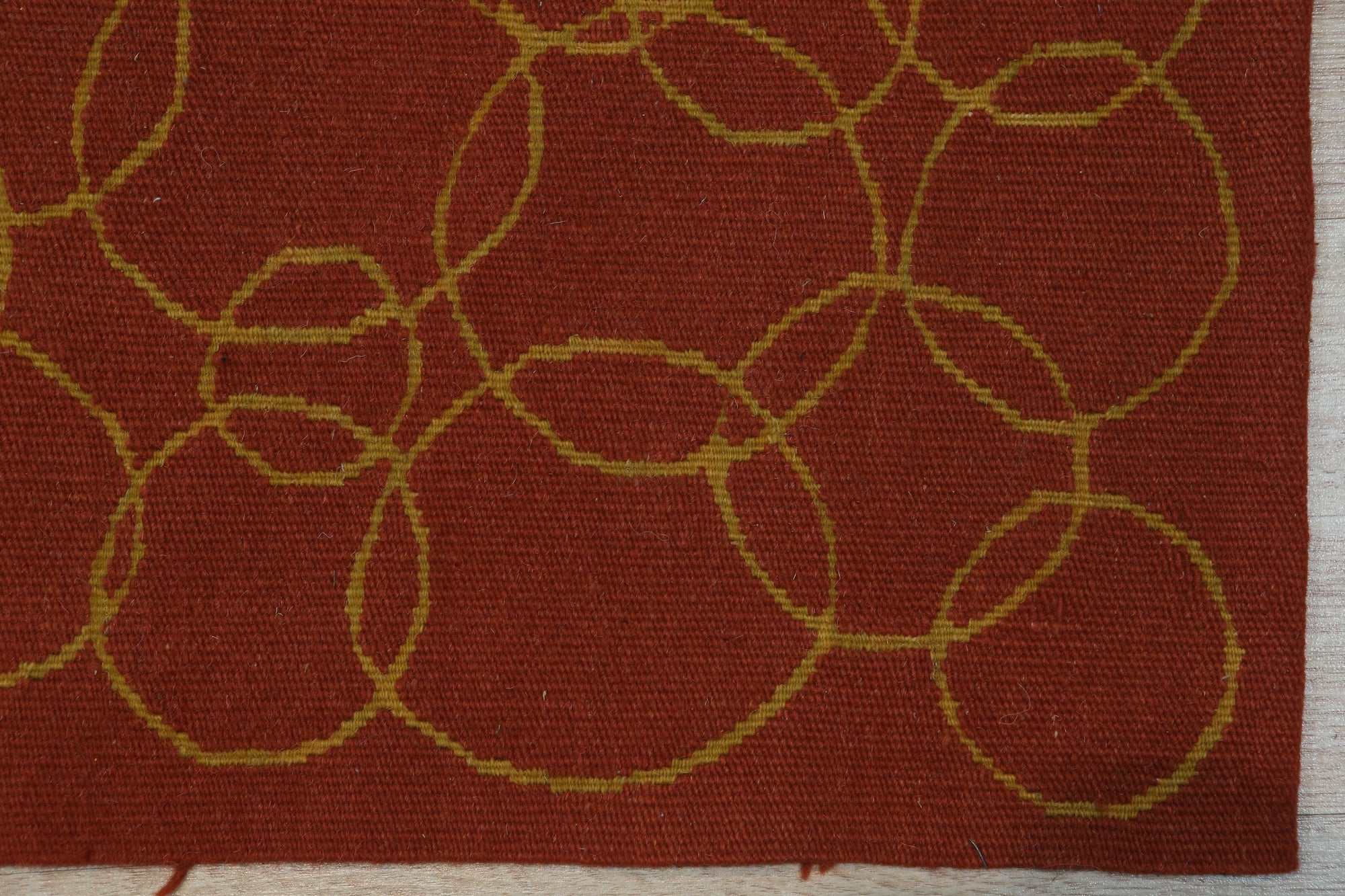 Nadia Lydia Red Flatweave Wool Rug displayed on light hardwood flooring, its vibrant red hue and flatweave construction grounding a minimalist space.
