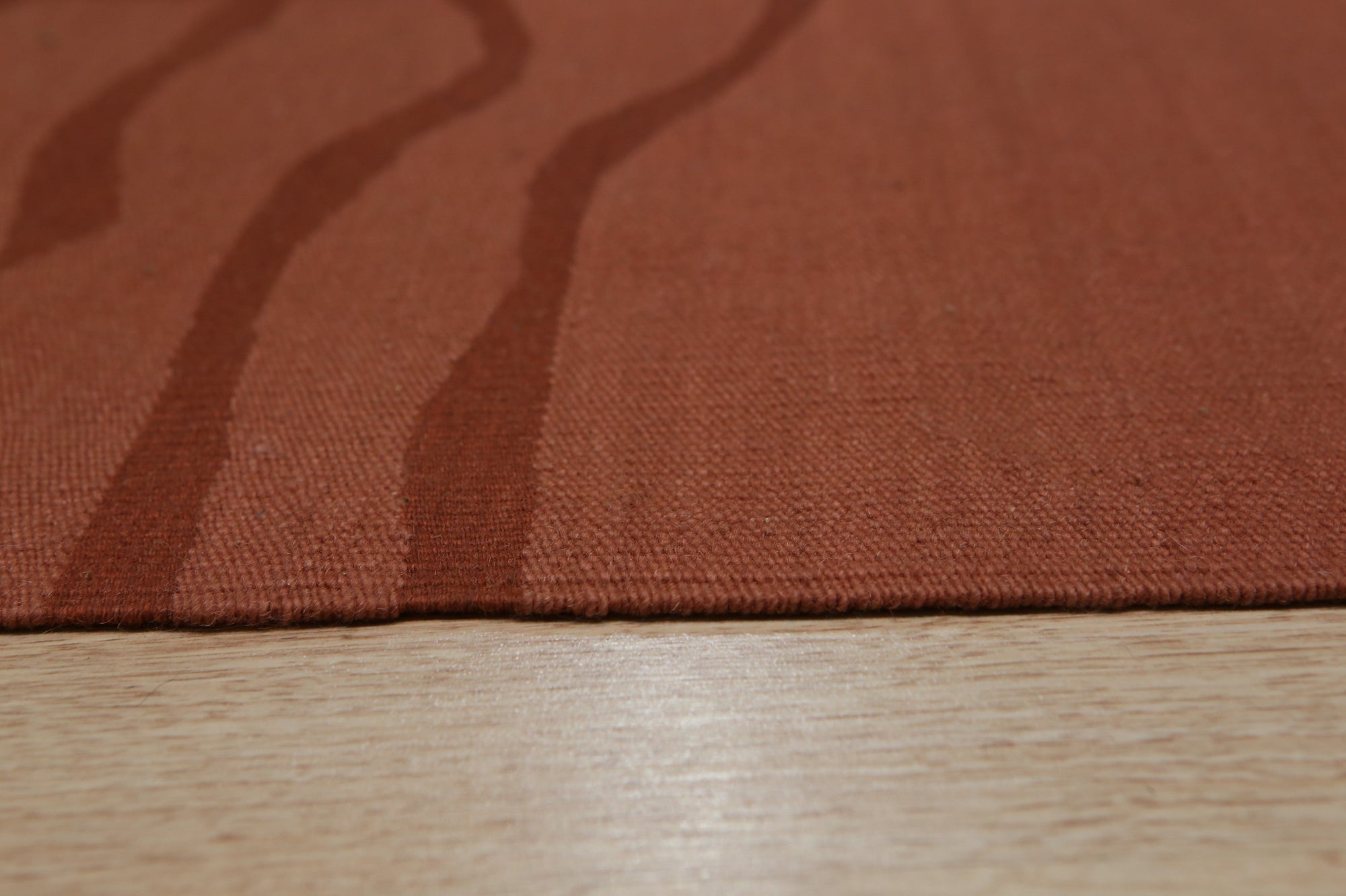 Inviting Maya Rust Flatweave Wool Rug, a textured flatweave in warm rust tones, adding earthy elegance to a softly lit living space.