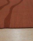 Inviting Maya Rust Flatweave Wool Rug, a textured flatweave in warm rust tones, adding earthy elegance to a softly lit living space.
