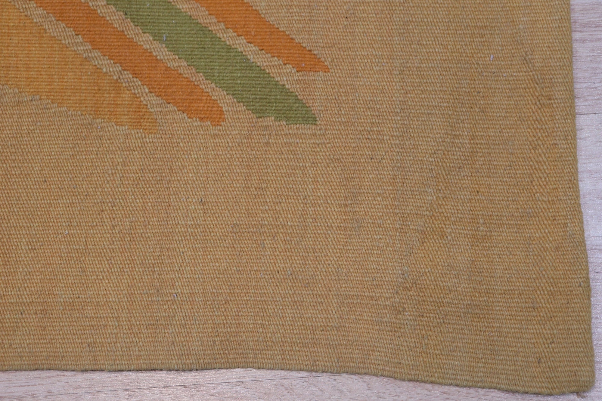 Sloane Maya Beige Flatweave Wool Rug, showcasing a living room setting. Warm light highlights the rug's flatweave construction and subtle beige tones, complementing the surrounding furniture and creating a cozy atmosphere.