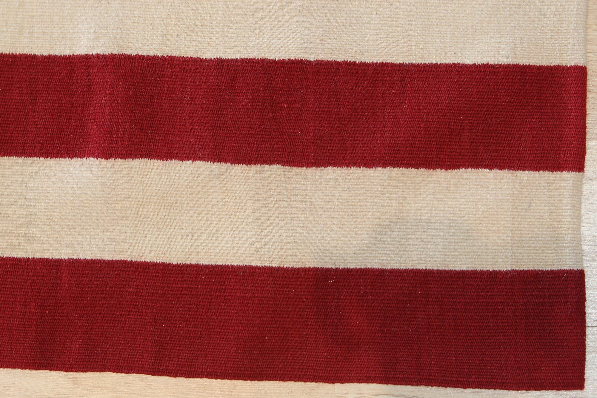 Maya Dazzling Usa Flatweave Wool Rug, showcasing a vibrant, geometric pattern of red, white, and blue hues across its flatwoven wool texture, displayed in a room setting.