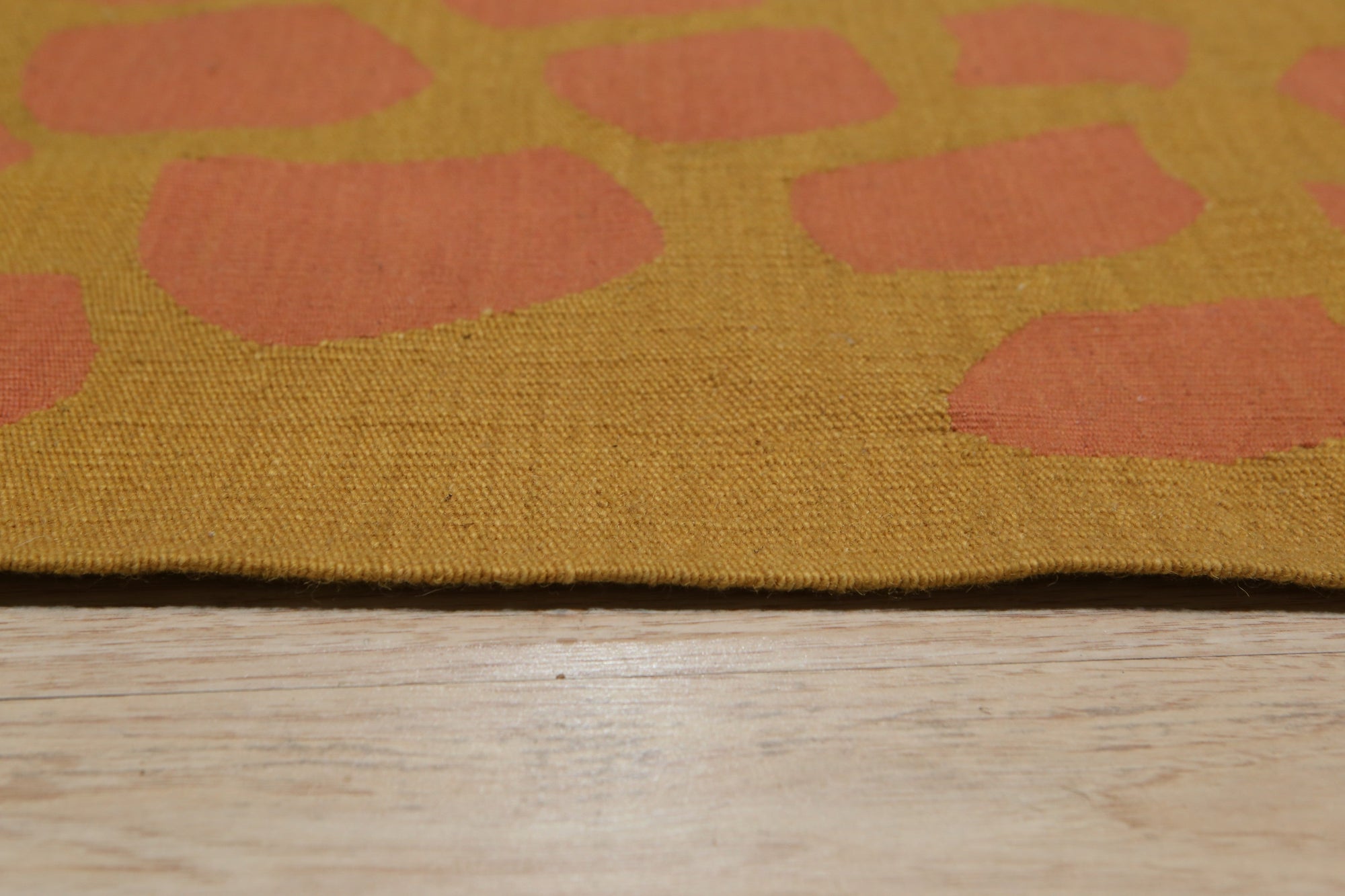 Amara Ruby Rust Flatweave Wool Rug, a textured flatweave rug with warm ruby and rust tones, enriching a living room setting with its subtle geometric pattern.