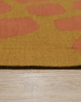 Amara Ruby Rust Flatweave Wool Rug, a textured flatweave rug with warm ruby and rust tones, enriching a living room setting with its subtle geometric pattern.