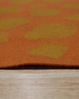 Artisan Handcrafted Rust Flatweave Wool Rug, its warm rust hues and flatweave texture grounding a softly lit living room.