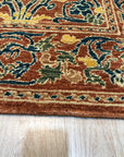 Elegant Warm Red Hand Knotted Wool Rug, its intricate floral patterns unfolding across a rich, warm red wool field, seen in a bright living space, suggesting comfort and timeless elegance.