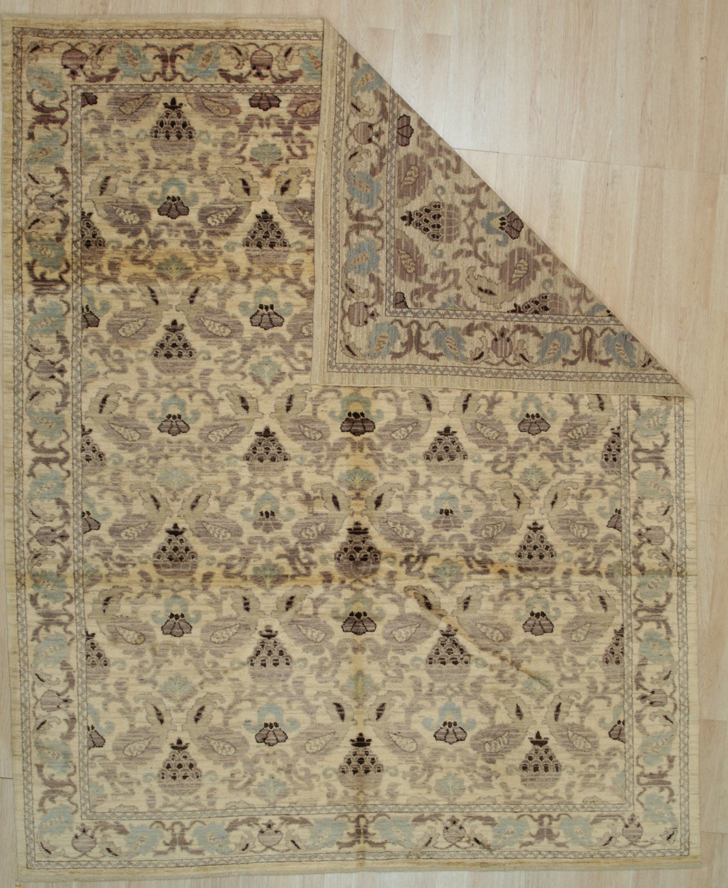 Vibrant Chloe Ivory Hand Knotted Wool Rug, showcasing intricate floral patterns and geometric borders in soft ivory hues, sits elegantly within a brightly lit living room setting.