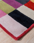 Captivating Amara Multicolored Hand Tufted Wool Rug, vibrant hues blend across a textured surface, grounding a contemporary living room with light wooden floors and a sleek grey sofa.