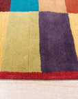 Captivating Amara Multicolored Hand Tufted Wool Rug, a vibrant, textured floor covering displaying a modern abstract pattern, lies in a bright living space, anchoring a seating arrangement with warm, inviting hues.