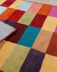 Captivating Amara Multicolored Hand Tufted Wool Rug, vibrant abstract patterns dance across a cozy living room floor, showcasing its hand-tufted texture and wool construction in a real-world setting.