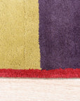 Captivating Amara Multicolored Hand Tufted Wool Rug displayed in a bright living room setting. Sunlight illuminates its vibrant hues and plush texture, showcasing its intricate hand-tufted construction and bold, modern design.