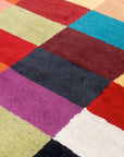 Captivating Amara Multicolored Hand Tufted Wool Rug, vibrant hues dance across a textured wool surface, grounding a modern living space with warmth and artistry.