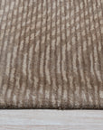 Sloane Freya Brown Hand Tufted Wool Rug, nestled on a light wood floor, features a textured geometric pattern in varying shades of brown, cream, and beige, creating a warm and inviting atmosphere.