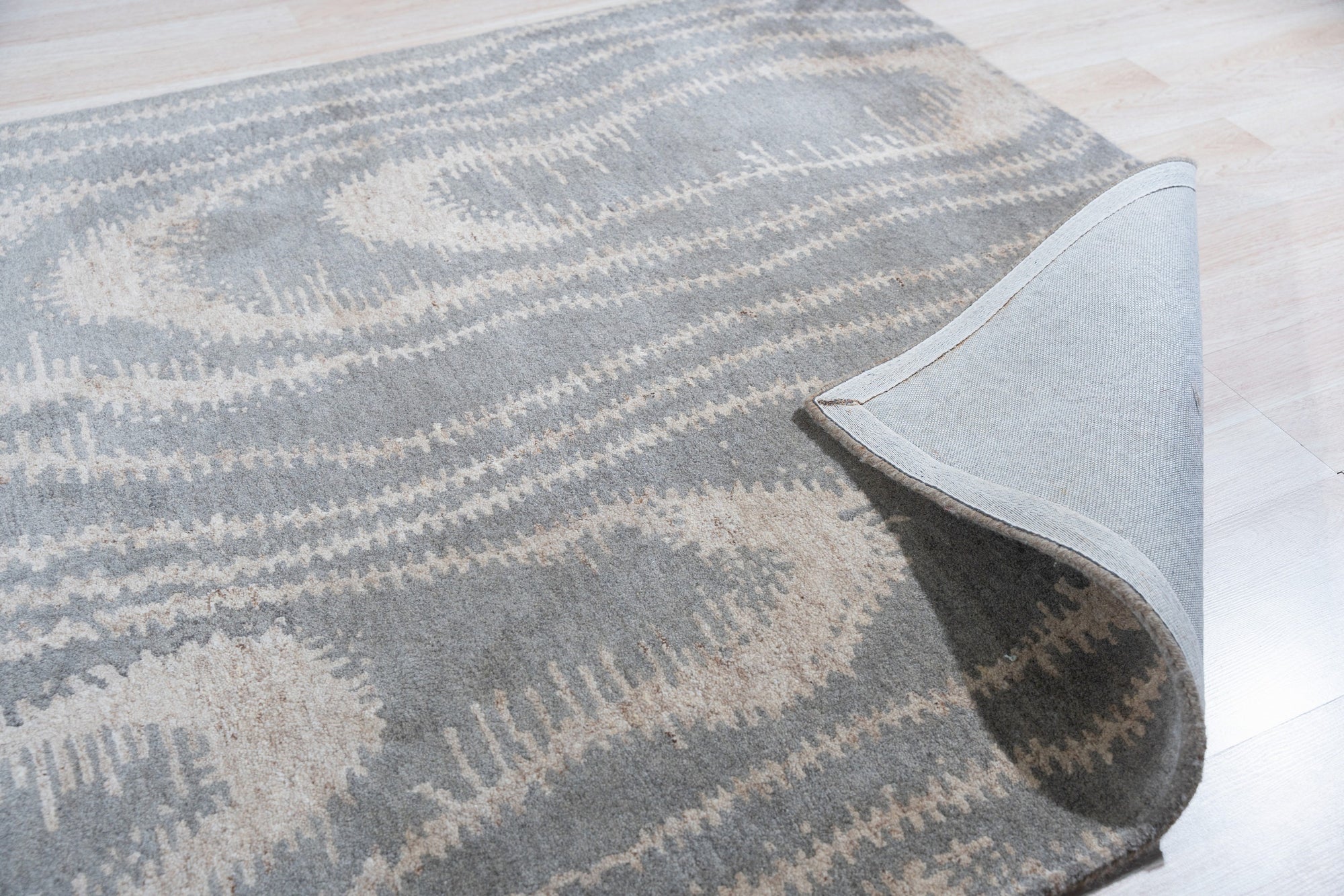 Graceful Captivating Gray Hand Tufted Wool Rug, a soft gray hand-tufted wool rug with a subtle, textured design, presented in a bright, modern living room setting.