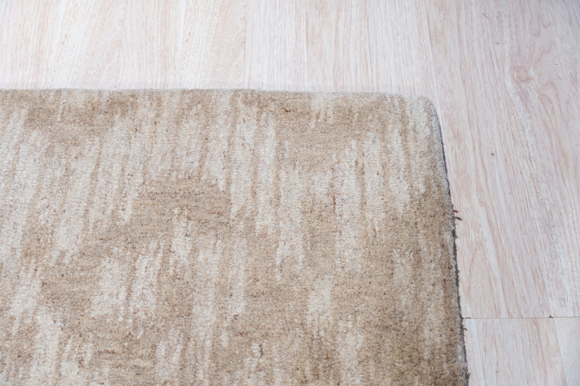 Vibrant Alluring Beige Hand Tufted Wool Rug, its creamy hues and plush texture grounding a bright living room. Neutral sofa and patterned pillows complement the rug's subtle beauty.