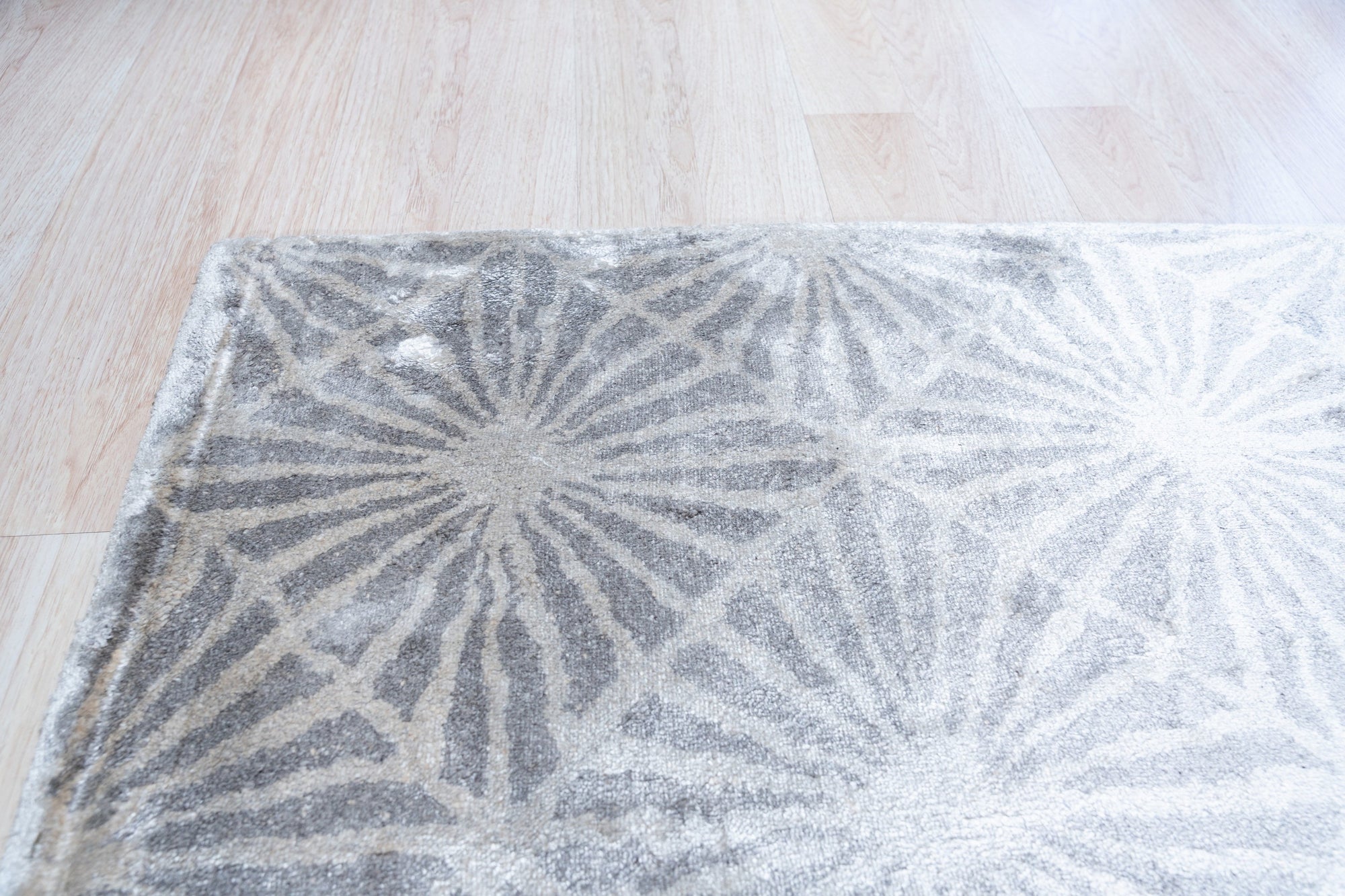 Trendy Timeless Gray Hand Tufted Wool Rug, its subtle variations in gray creating a textured, inviting surface on a polished wood floor in a bright, modern living space.