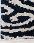 Luna Willow Black, White Hand Tufted Wool Rug displayed in a bright, modern living space. The geometric pattern of black and white wool contrasts against a light wooden floor, adding a striking focal point to the room.