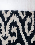 Luna Willow Black, White Hand Tufted Wool Rug featuring a graphic, abstract pattern, anchors a bright living room. Natural light illuminates the rug's plush wool texture and bold monochrome design, contrasting with the warm wood flooring.