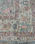 Refined Fiona Blue Handmade Wool Rug, displaying intricate patterns in cool blues and creams, lays flat on a light hardwood floor, inviting warmth and subtle sophistication into a modern space.