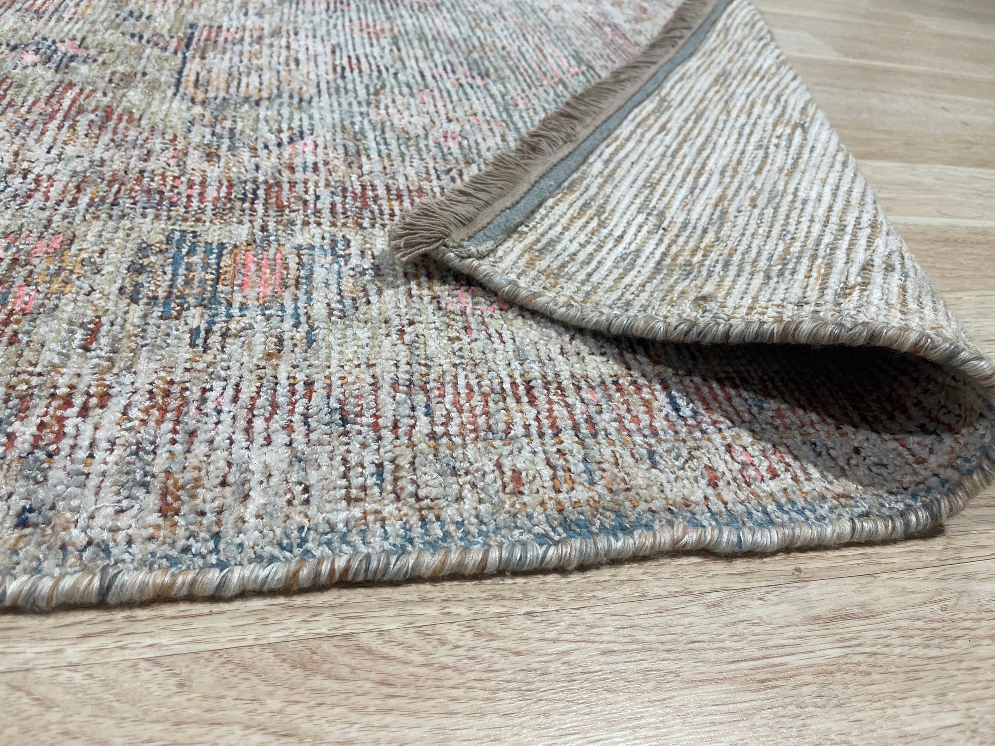Fiona Vibrant Ivory Handmade Wool Rug, warm and inviting, lies beneath a modern coffee table adorned with books and a succulent; its plush ivory wool provides a soft contrast to the dark wood floor, creating a cozy and stylish living space.