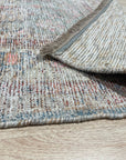 Fiona Vibrant Ivory Handmade Wool Rug, warm and inviting, lies beneath a modern coffee table adorned with books and a succulent; its plush ivory wool provides a soft contrast to the dark wood floor, creating a cozy and stylish living space.
