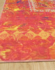 Xena Artistic Multicolor Machine Made Rug, vibrant abstract patterns in shades of blue, orange, and cream create a modern focal point in a bright living room setting.