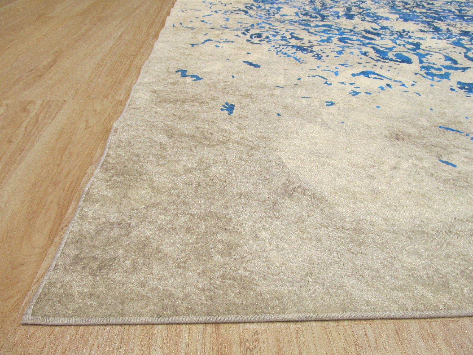 Modern Classic Blue Machine Made Rug featuring swirling patterns of navy and cream, lying flat on a light-colored floor, inviting comfort and elegance into any space.
