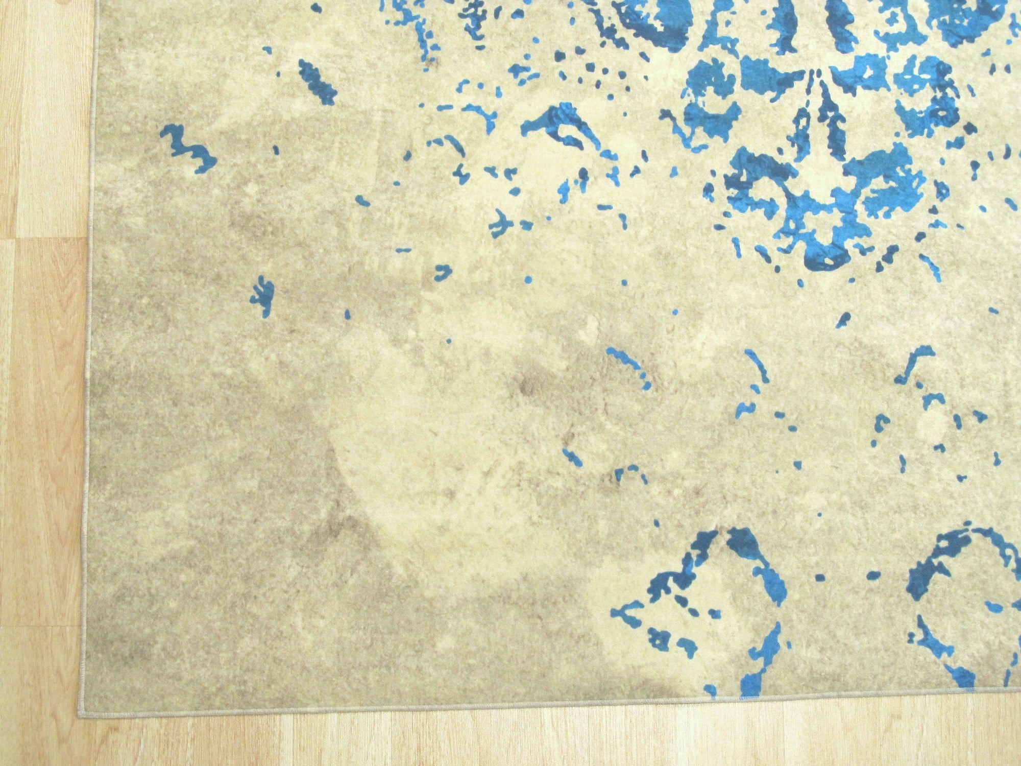 Modern Classic Blue Machine Made Rug, showcasing intricate geometric patterns in shades of blue and beige, lies on a dark wood floor, creating a sophisticated and inviting ambiance.