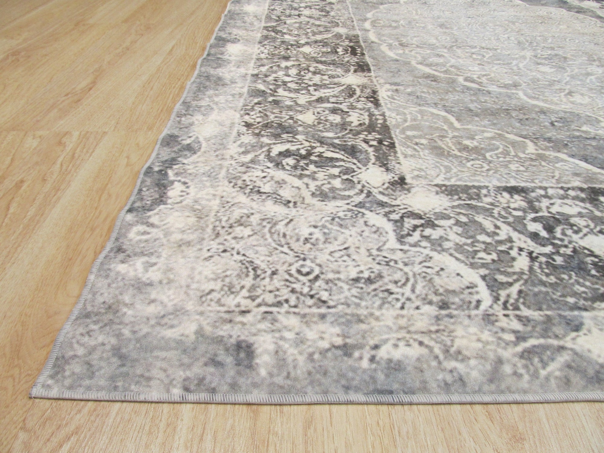 Bianca Warm Gray Machine Made Rug displayed in a bright, modern living room. Soft, warm gray tones and subtle geometric pattern complement neutral furniture, creating a cozy and inviting atmosphere. Machine-made construction offers durability and easy care.
