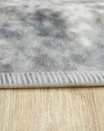 Bianca Warm Gray Machine Made Rug displayed, revealing subtle texture and warm grey tones against a light wood floor and white furniture, suggesting a contemporary living space.