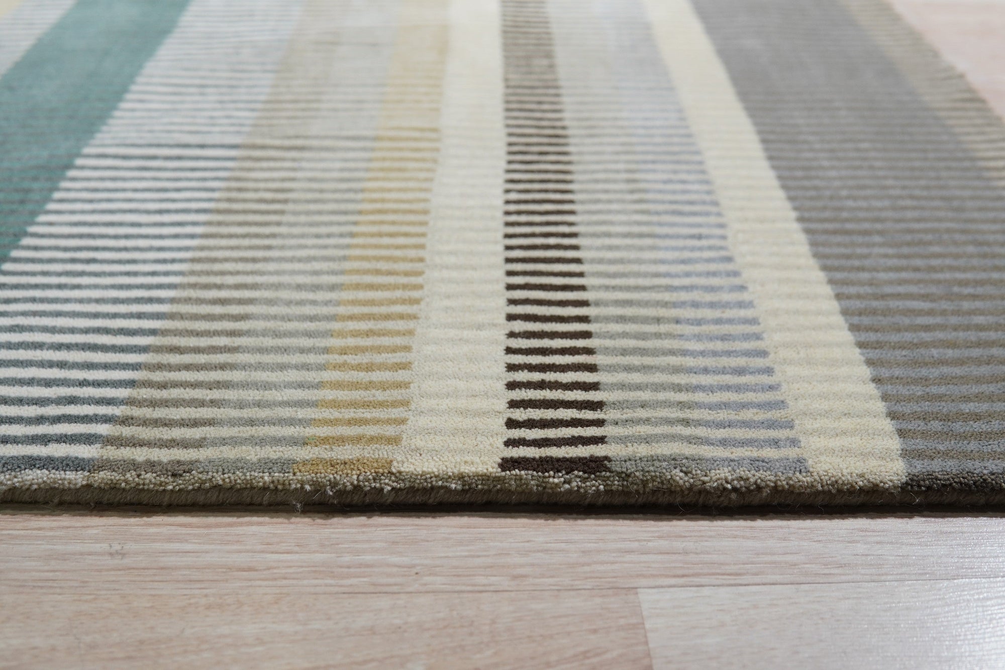 Zinnia Striped Green Handmade Wool Rug displayed in a bright, modern living room. Green and cream stripes create a cheerful, inviting atmosphere. Woven wool texture visible, showcasing the rug's handmade construction.