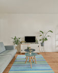 Serene Xena Green Handmade Wool Rug, a textured expanse of verdant green and subtle neutral tones, anchors a softly lit living space, its hand-woven wool pile inviting touch.