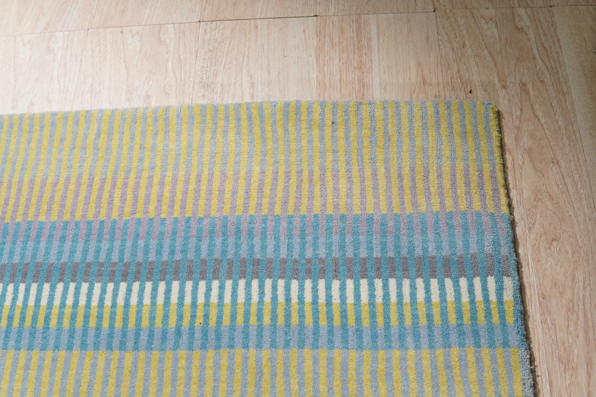 Serene Xena Green Handmade Wool Rug, showcasing a blend of muted and vibrant greens in a subtly textured weave, situated within a living room setting with contemporary furniture.