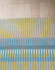 Serene Xena Green Handmade Wool Rug, showcasing a blend of muted and vibrant greens in a subtly textured weave, situated within a living room setting with contemporary furniture.