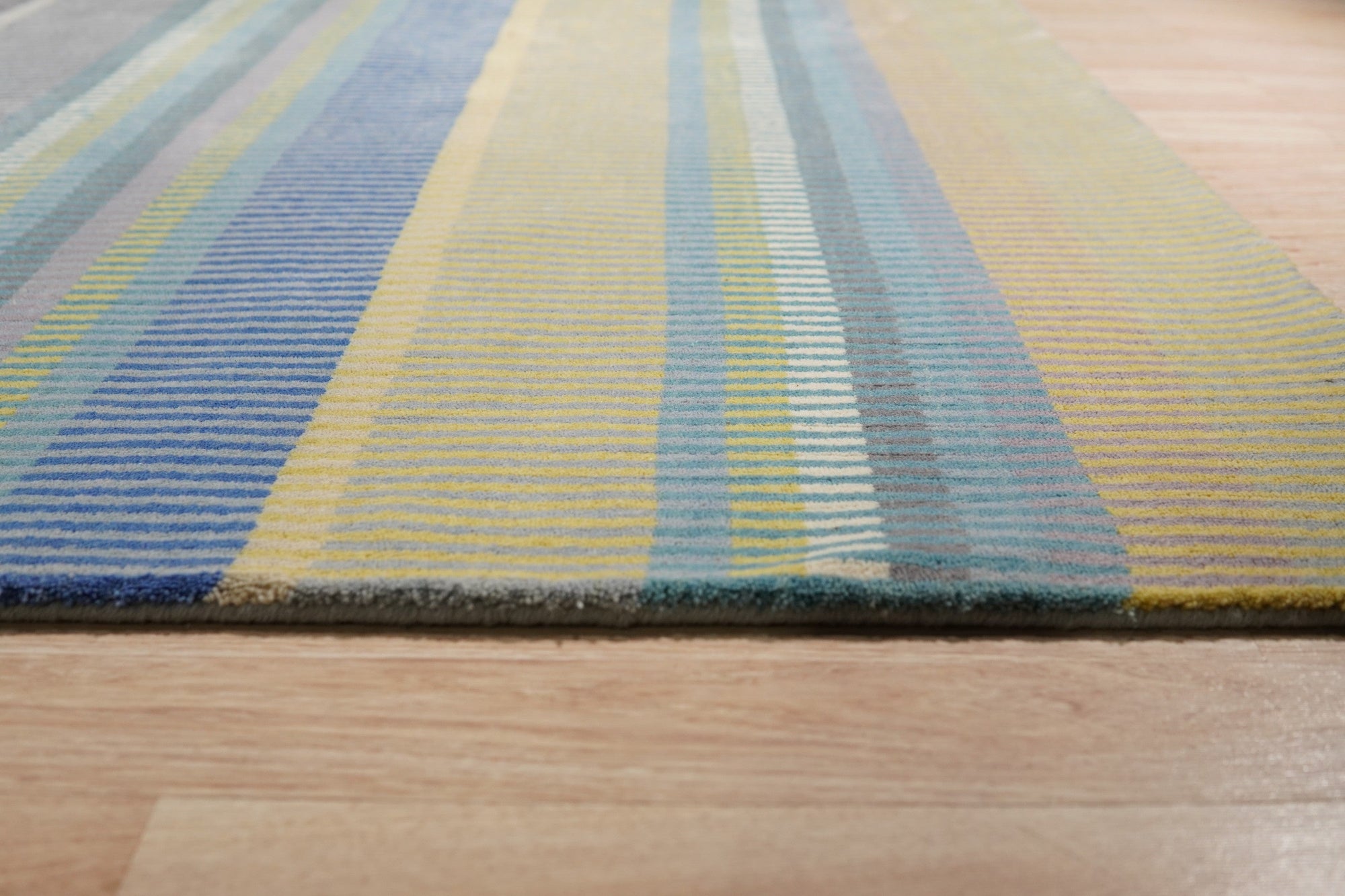 Serene Xena Green Handmade Wool Rug, showcasing its calming green tones and textured wool construction in a bright, modern living room setting with light wood floors.