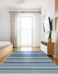 Comfortable Striped Lavender Handmade Wool Rug, soft bands of lavender, cream, and beige wool create a soothing striped pattern, subtly textured and lying elegantly on a light wood floor, bathed in natural light.