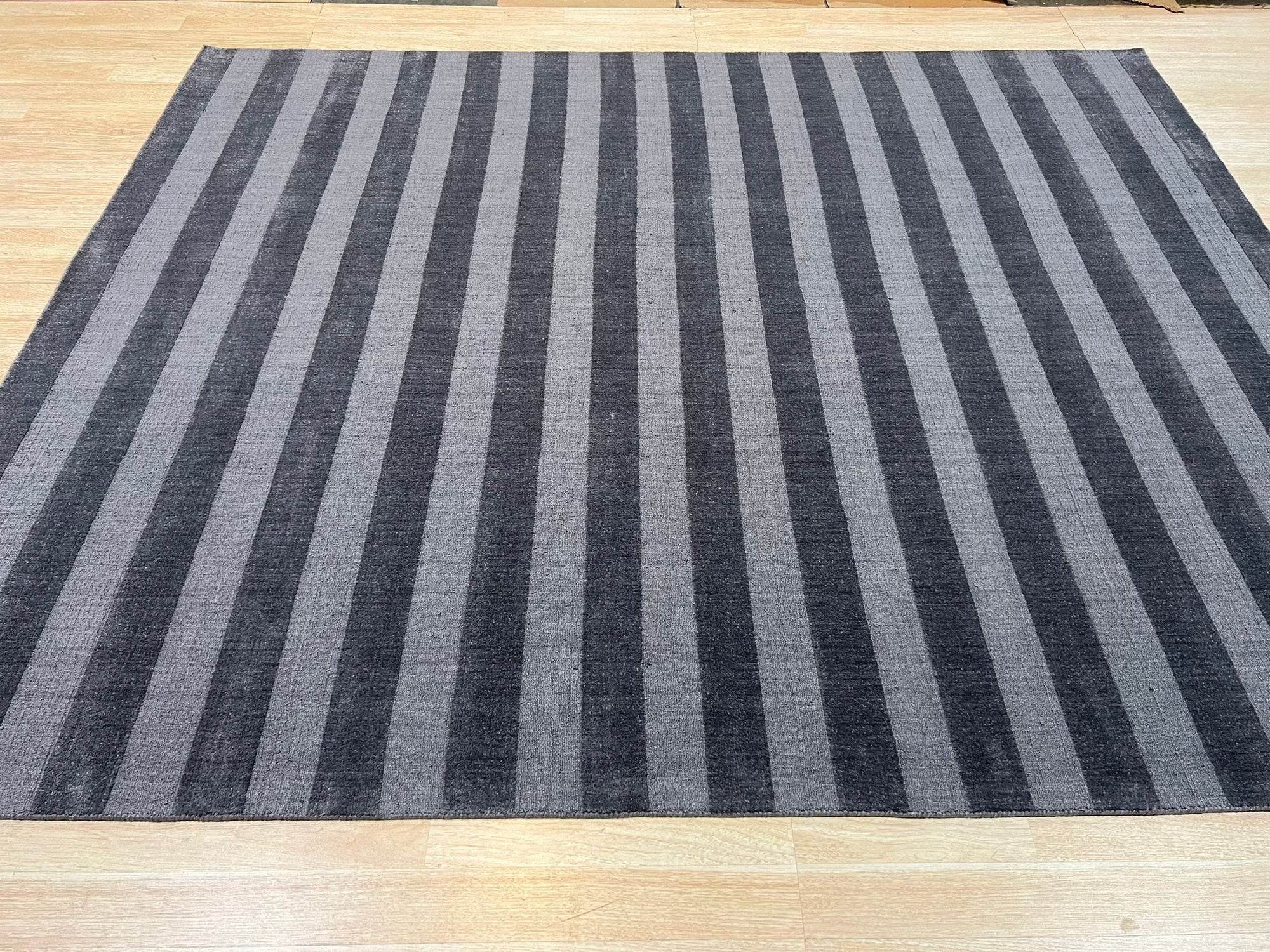Yara Alluring Gray Handmade Wool Rug, displaying subtle variations in gray tones and textures, grounding a bright living room with modern furniture.