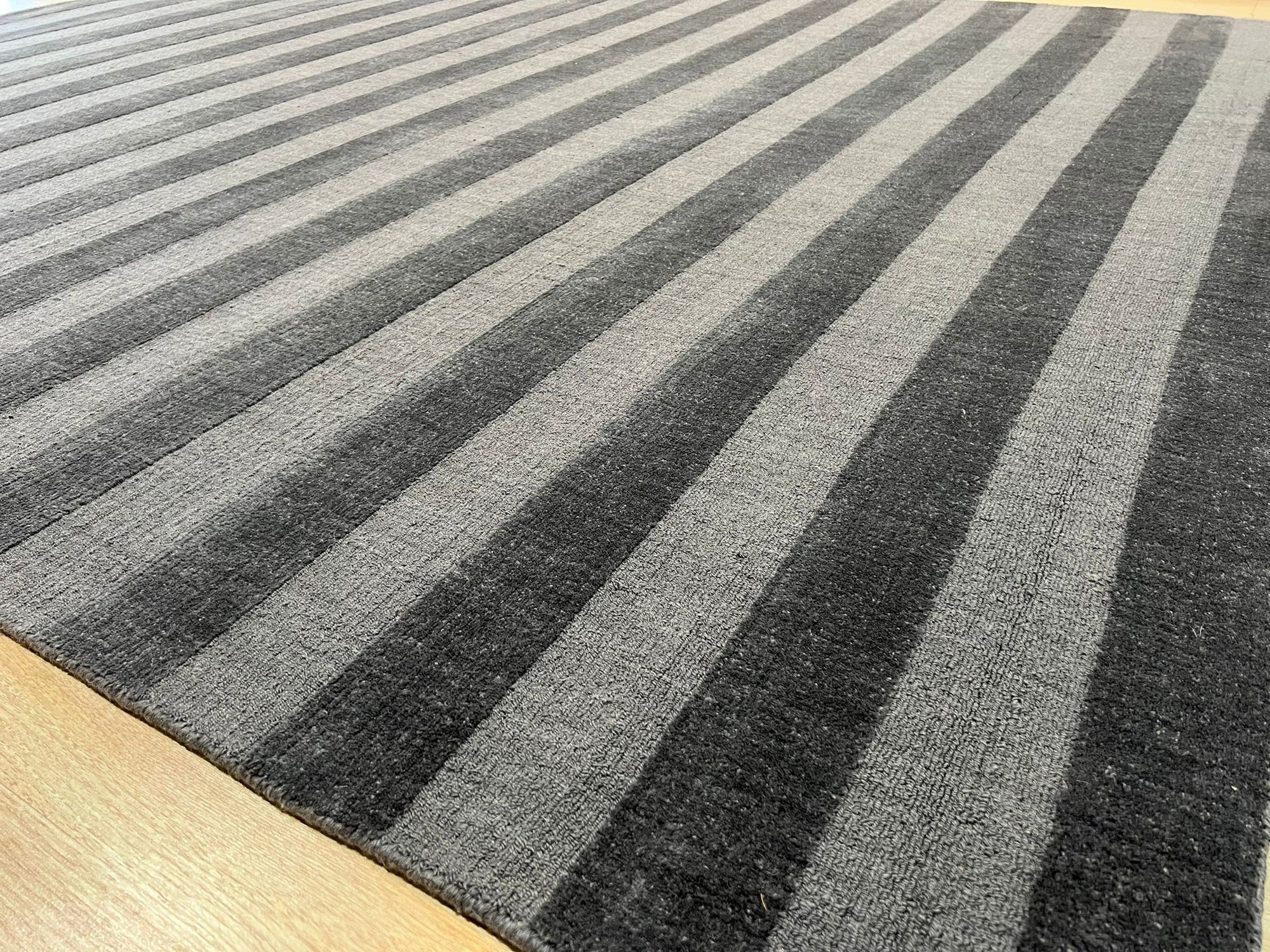 Yara Alluring Gray Handmade Wool Rug, blending cool grays in a textured, inviting weave, graces a well-lit space, adding warmth and sophistication.