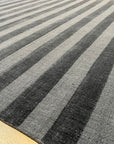 Yara Alluring Gray Handmade Wool Rug, blending cool grays in a textured, inviting weave, graces a well-lit space, adding warmth and sophistication.