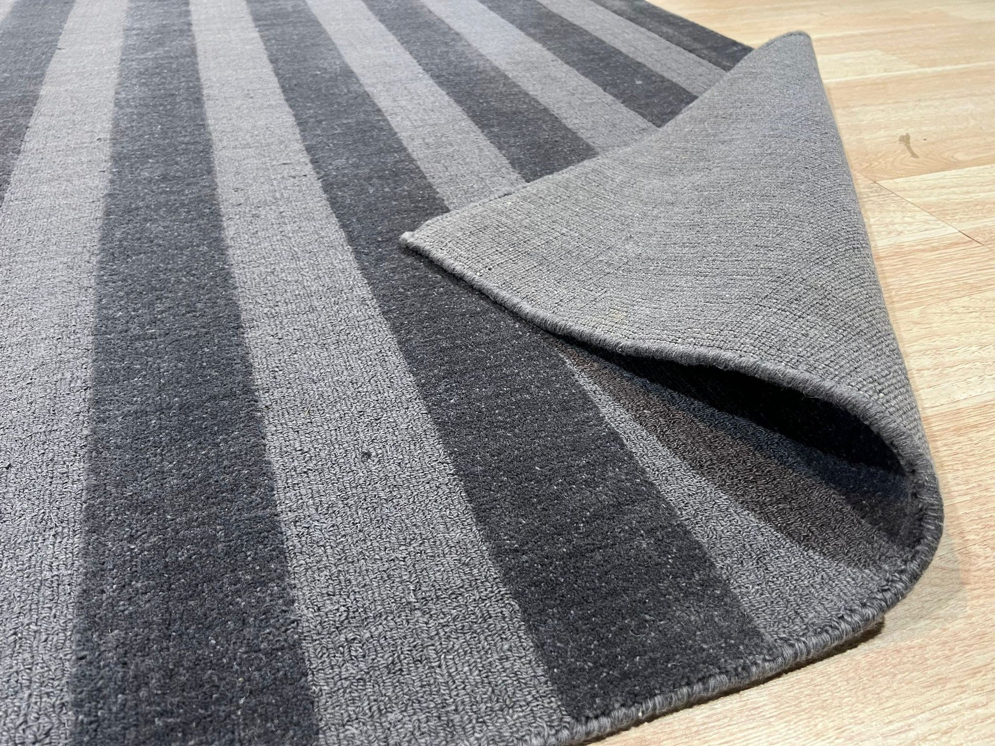 Yara Alluring Gray Handmade Wool Rug, showcasing its subtle variations in gray wool, textured weave, and plush feel, complementing a modern living room with minimalist decor and a warm, inviting ambiance.